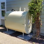 A cream colored tank installed next to a building with siding.