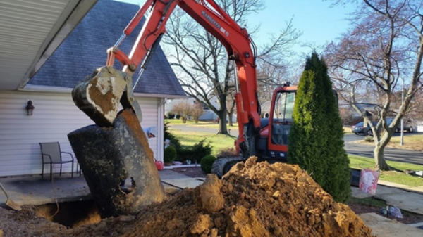 Excavator pulling out a buried residential oil tank