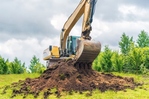 Tractor digging up dirt for soil remediation