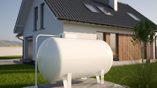 A white oil tank outside of a house.