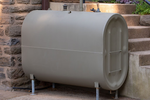 An above oil tank installed outdoors near concrete steps.