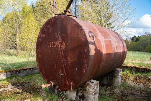 A very old red oil tank sits abandoned.